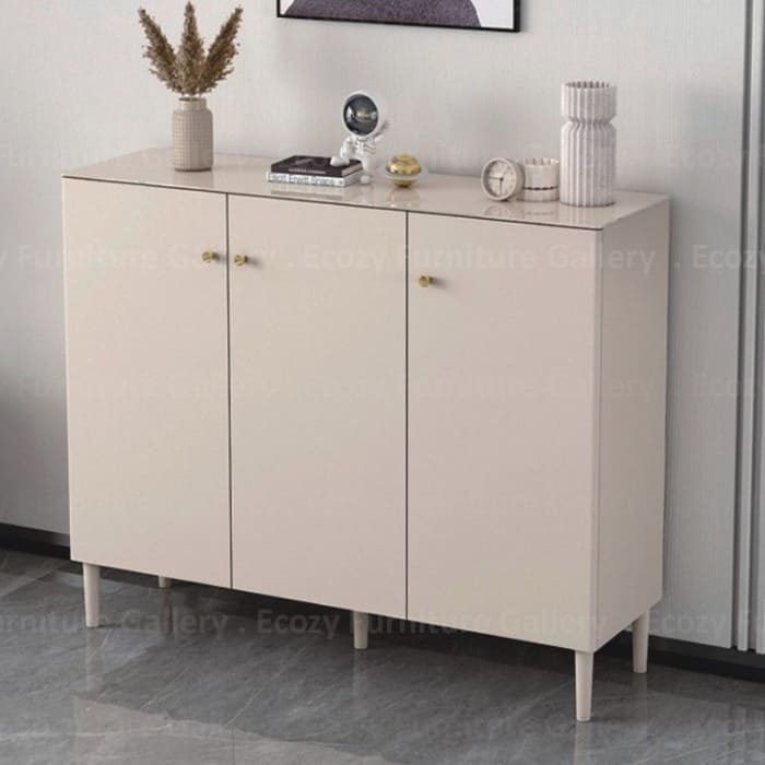 Shoe cabinet with three doors, featuring gold color handles, styled with decorative items on top