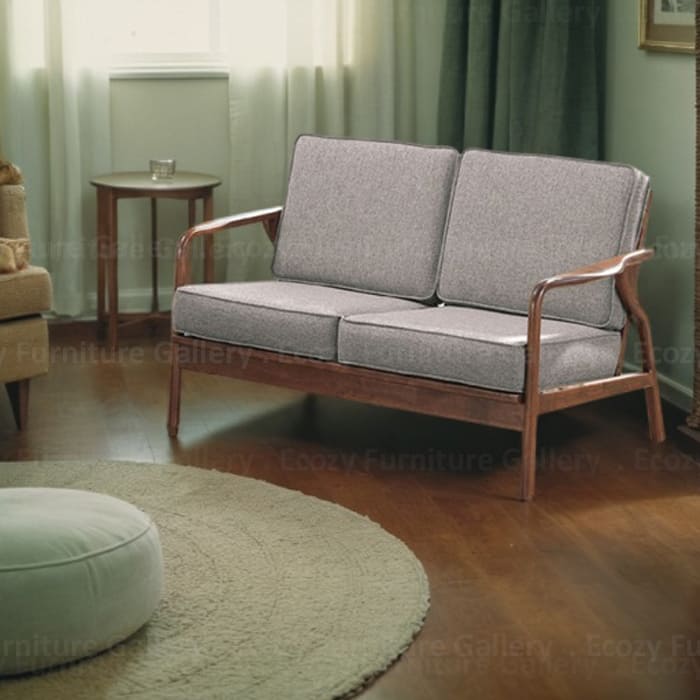 Wooden Sofa with a light brown fabric cushion, featuring wooden armrests and a sleek design, set in a cozy living room with warm lighting and wooden flooring